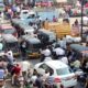 Crowded urban street with cars, bikes, and auto rickshaws in bustling city traffic.
