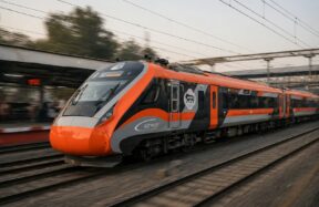 An orange and grey train speeds down the tracks