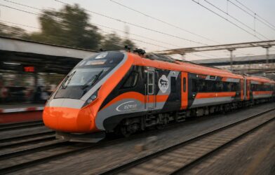 An orange and grey train speeds down the tracks