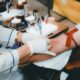 A healthcare worker in white gloves drawing blood from a person's arm