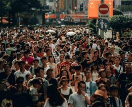 A dense crowd of people walking along a busy city street