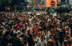 A dense crowd of people walking along a busy city street