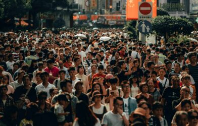A dense crowd of people walking along a busy city street