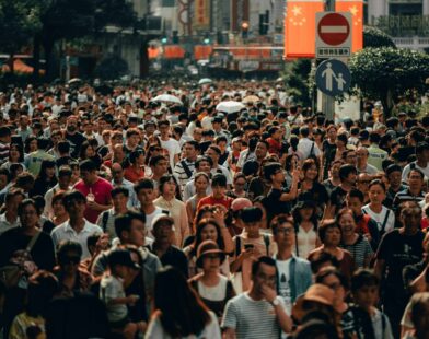 A dense crowd of people walking along a busy city street