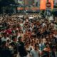 A dense crowd of people walking along a busy city street