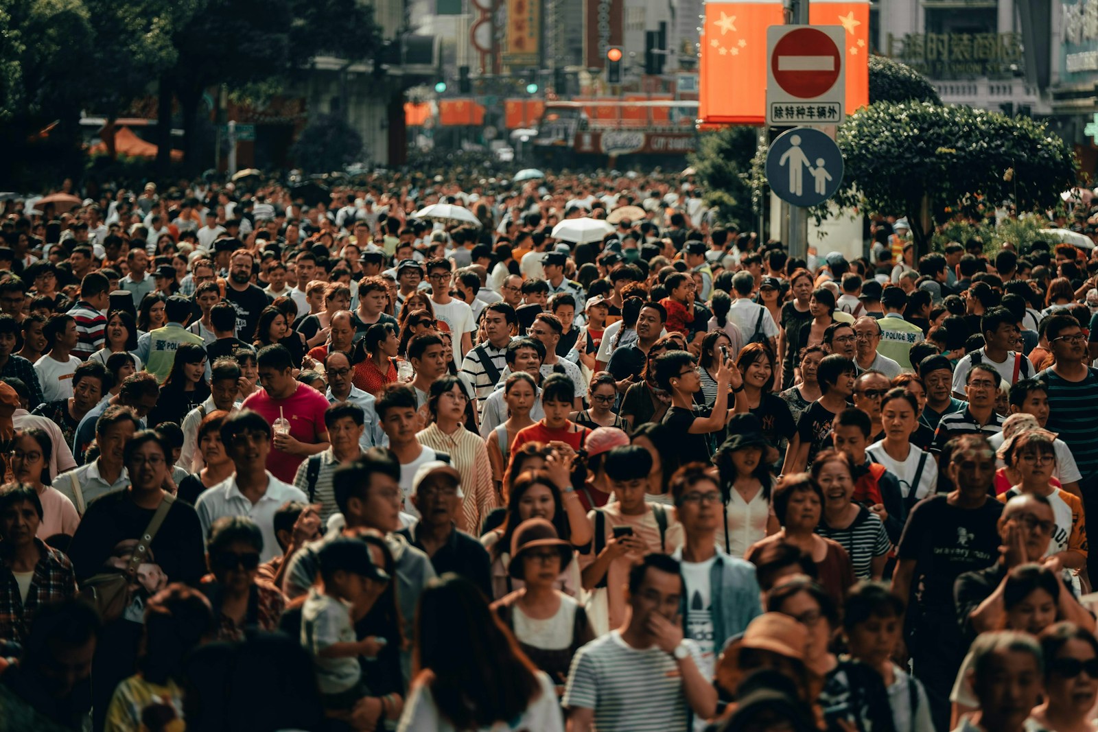 A dense crowd of people walking along a busy city street