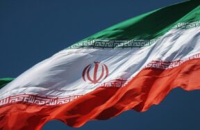 The flag of Iran waving against a clear dark blue sky