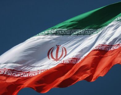 The flag of Iran waving against a clear dark blue sky