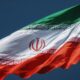 The flag of Iran waving against a clear dark blue sky