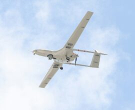 A small airplane flying through a blue sky