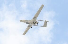 A small airplane flying through a blue sky