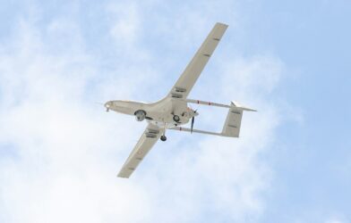 A small airplane flying through a blue sky