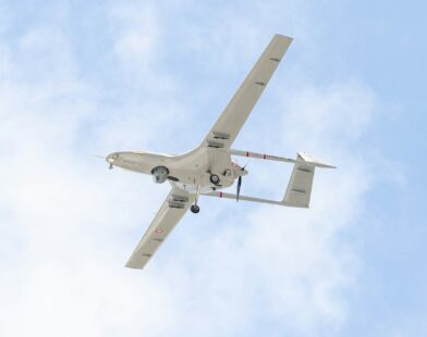 A small airplane flying through a blue sky
