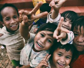 five children smiling while doing peace hand sign