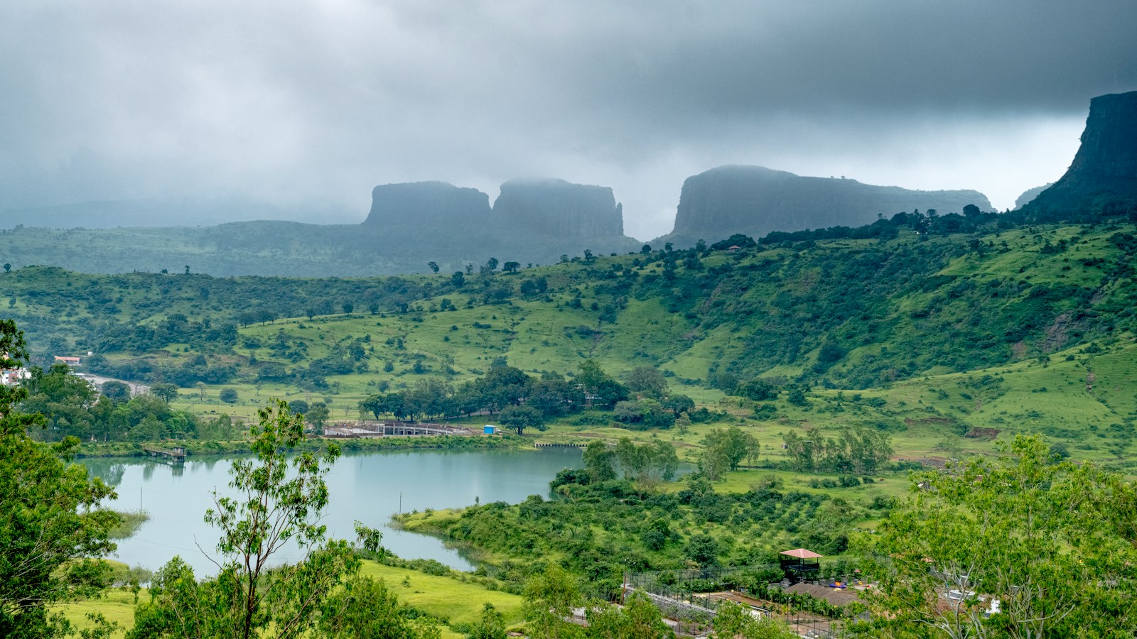 a landscape with trees and a body of water with mountains in the background