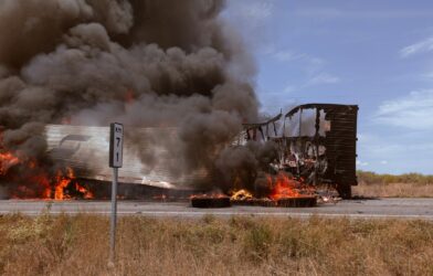 A large truck on fire on the side of the road