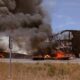A large truck on fire on the side of the road