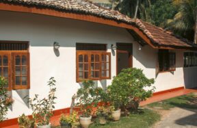 A white house has wooden windows and a red roof