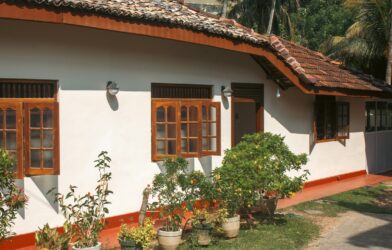 A white house has wooden windows and a red roof