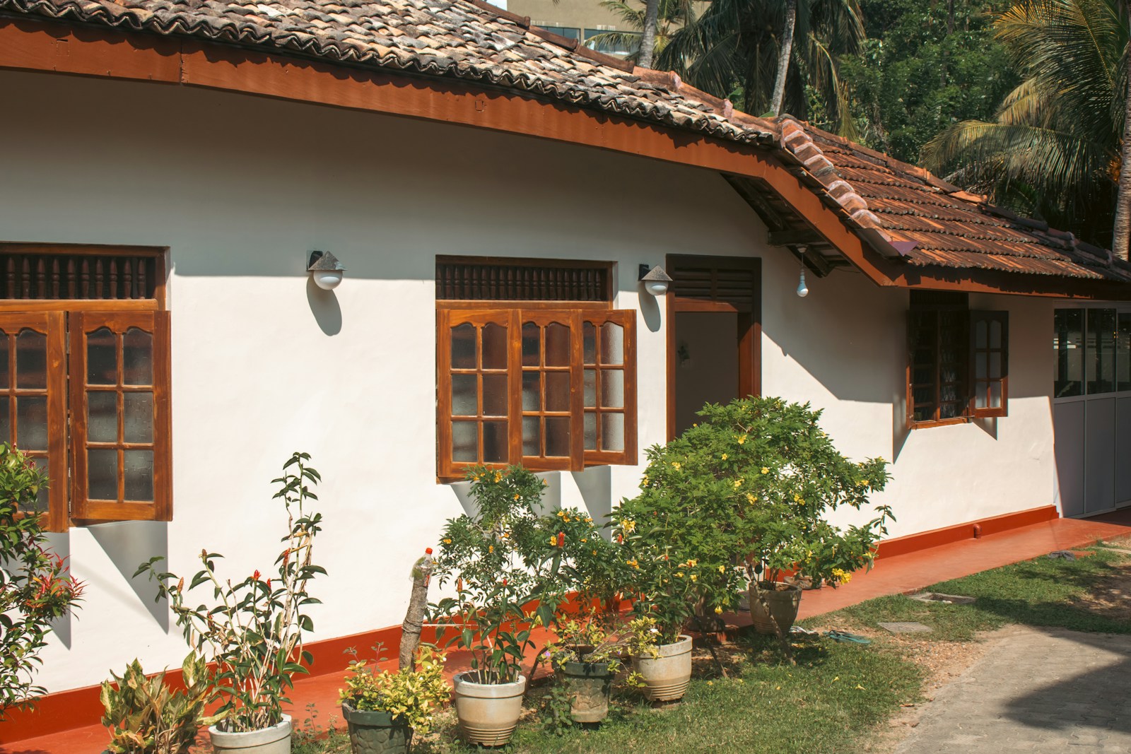 A white house has wooden windows and a red roof