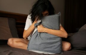 A woman sitting on a bed holding a pillow