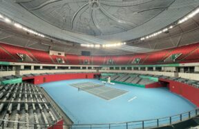 a tennis court with a blue floor and red seats