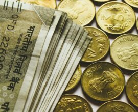 round gold-colored rupee coins and banknotes