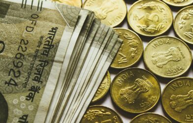 round gold-colored rupee coins and banknotes