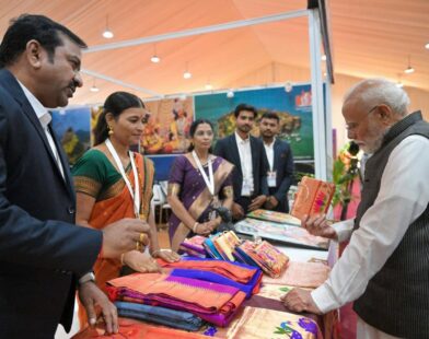 पंतप्रधान नरेंद्र मोदी महाराष्ट्राच्या पर्यटन दालनात पैठणी साड्यांची पाहणी करताना