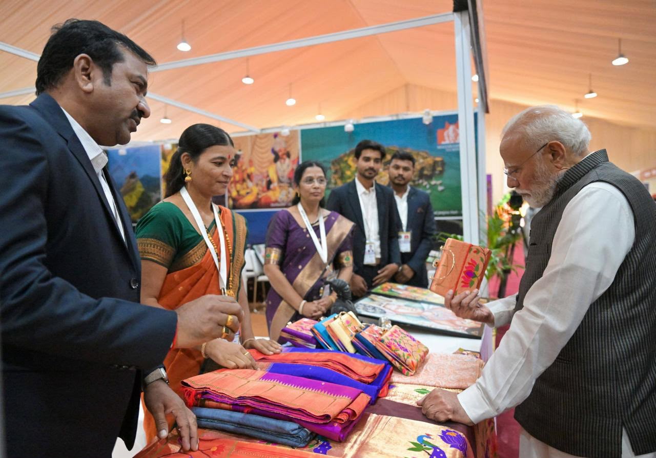 पंतप्रधान नरेंद्र मोदी महाराष्ट्राच्या पर्यटन दालनात पैठणी साड्यांची पाहणी करताना