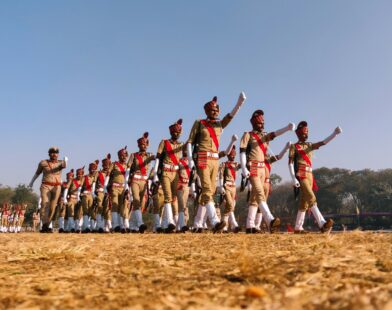 group of people in red and white shirts and pants jumping on brown field during daytime