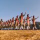 group of people in red and white shirts and pants jumping on brown field during daytime