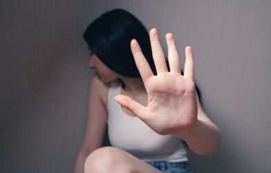 woman in white tank top covering face with her hands