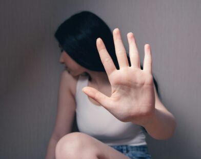 woman in white tank top covering face with her hands
