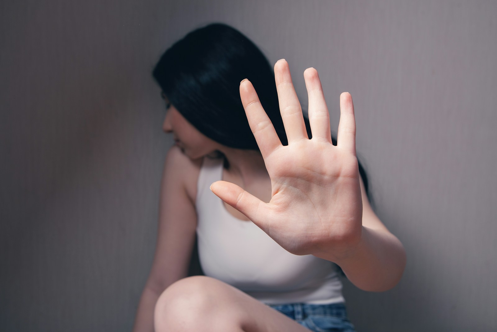 woman in white tank top covering face with her hands