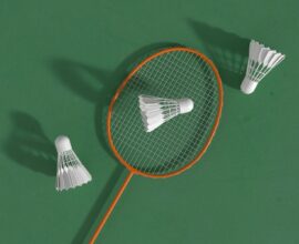 a badminton racket and two shuttles on a green surface