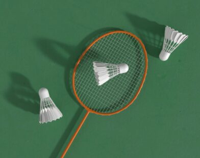a badminton racket and two shuttles on a green surface