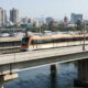 A modern train travels on an elevated track over water