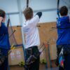 Three archers aiming at targets in an indoor range