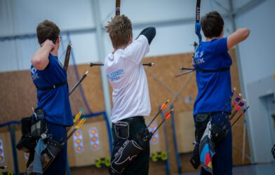 Three archers aiming at targets in an indoor range