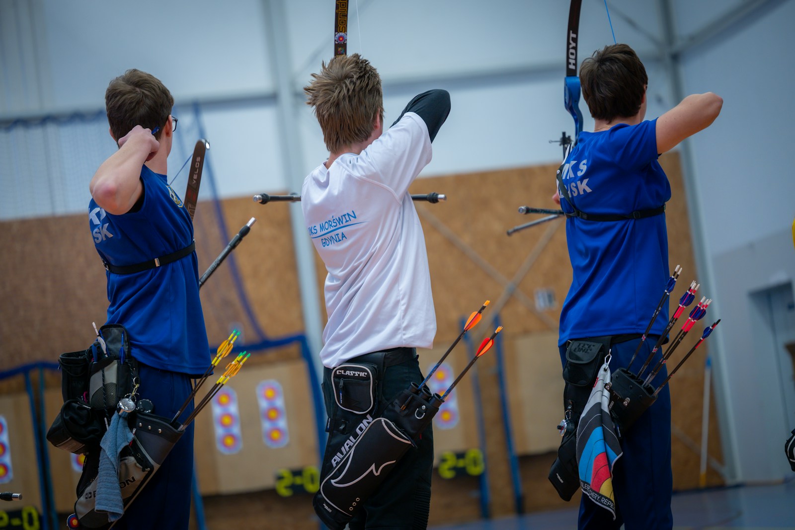 Three archers aiming at targets in an indoor range
