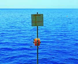 a sign on a pole in the middle of a body of water