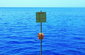 a sign on a pole in the middle of a body of water