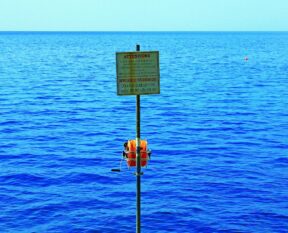 a sign on a pole in the middle of a body of water