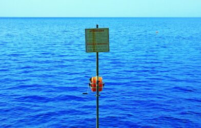 a sign on a pole in the middle of a body of water