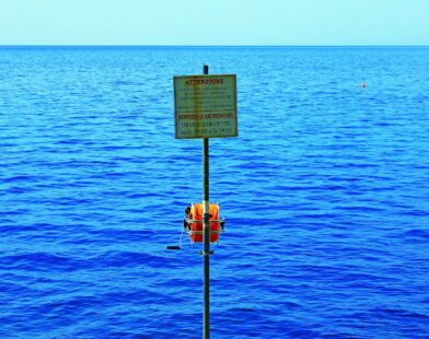 a sign on a pole in the middle of a body of water