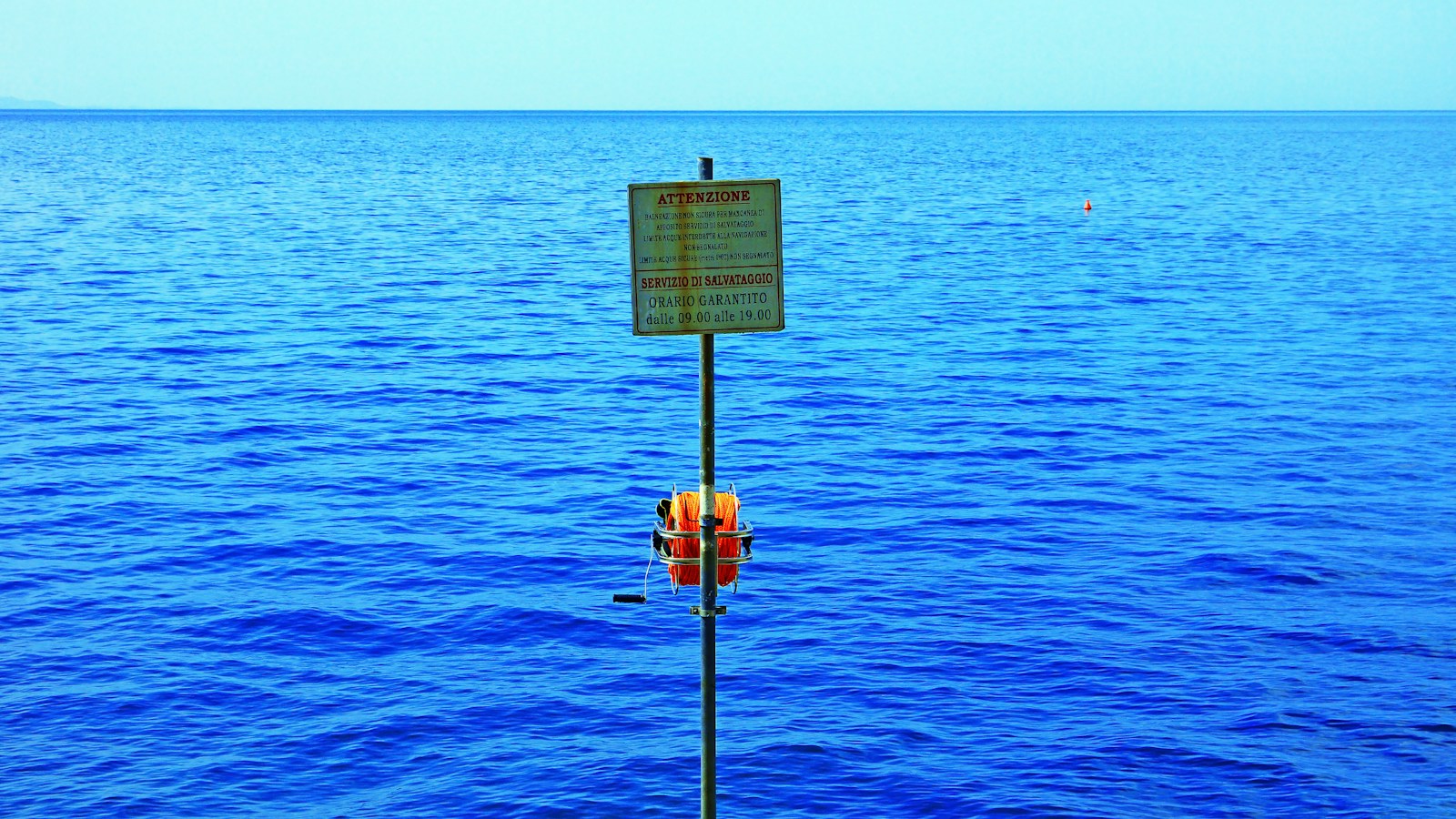 a sign on a pole in the middle of a body of water