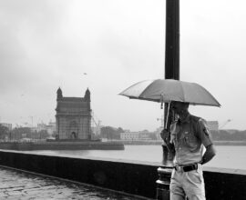 A person standing on a bridge with an umbrella