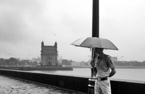 A person standing on a bridge with an umbrella