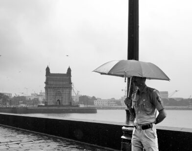 A person standing on a bridge with an umbrella